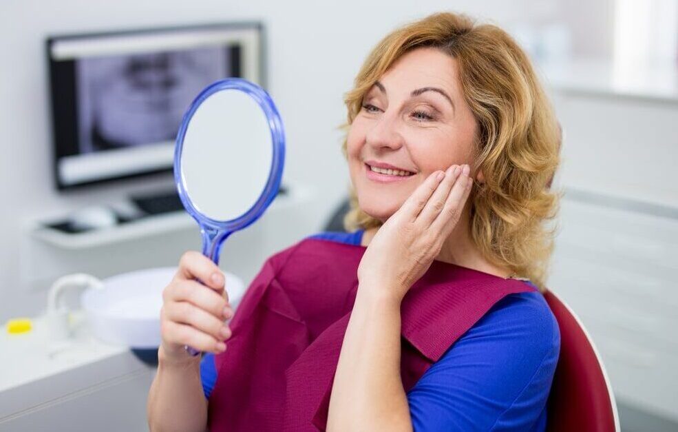 cheerful mature woman looking at her teeth in dental clinic