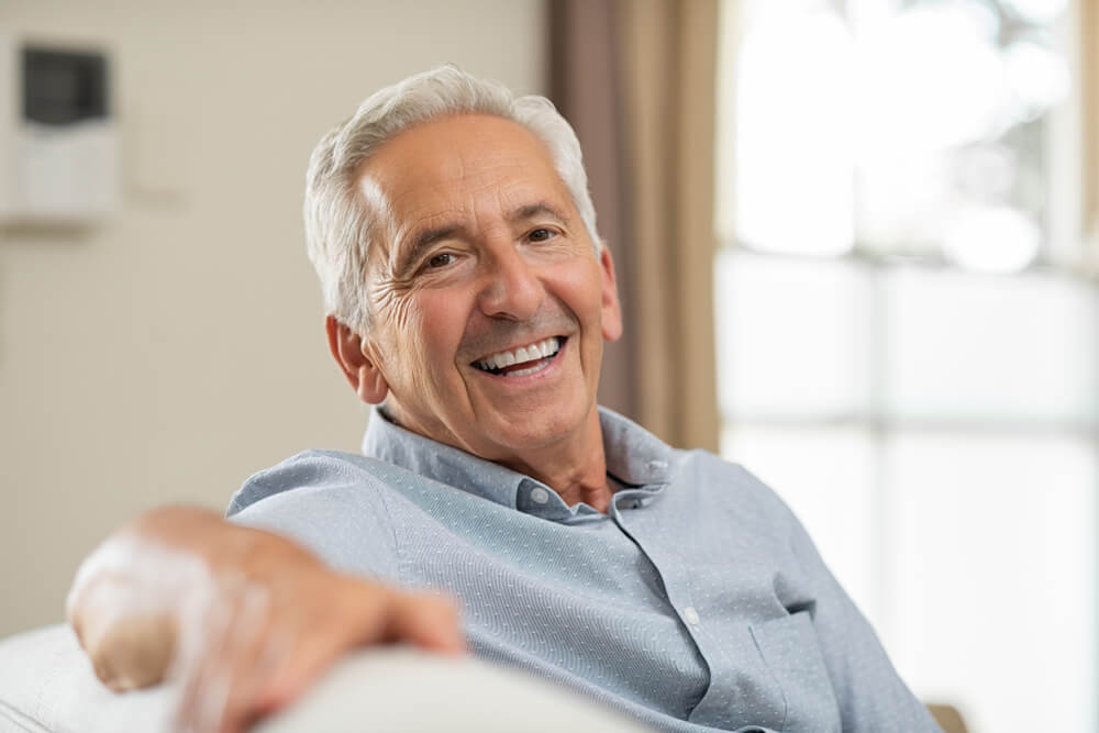 Old man relaxing on sofa and looking at camera