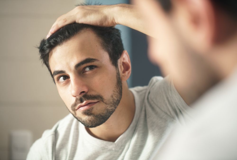 A man looking at his hair line thinking about getting treatments for Hair Regrowth