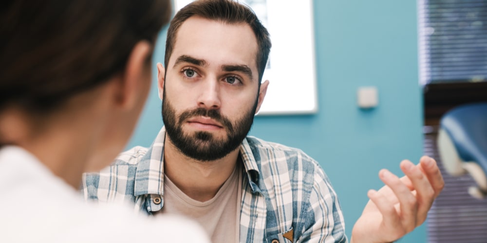 young patient man talking about health treatment in hospital room