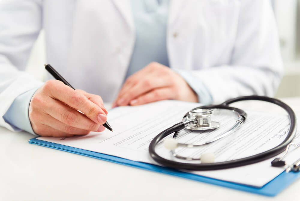 Young woman physician with stethoscope prescribing treatment to patient