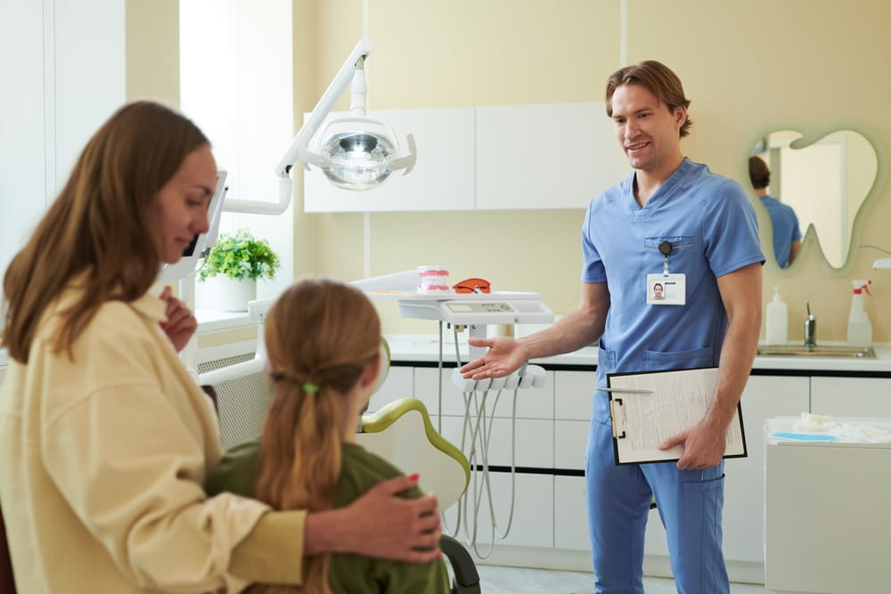 Caucasian male dentist greeting Caucasian woman and child in dental clinic