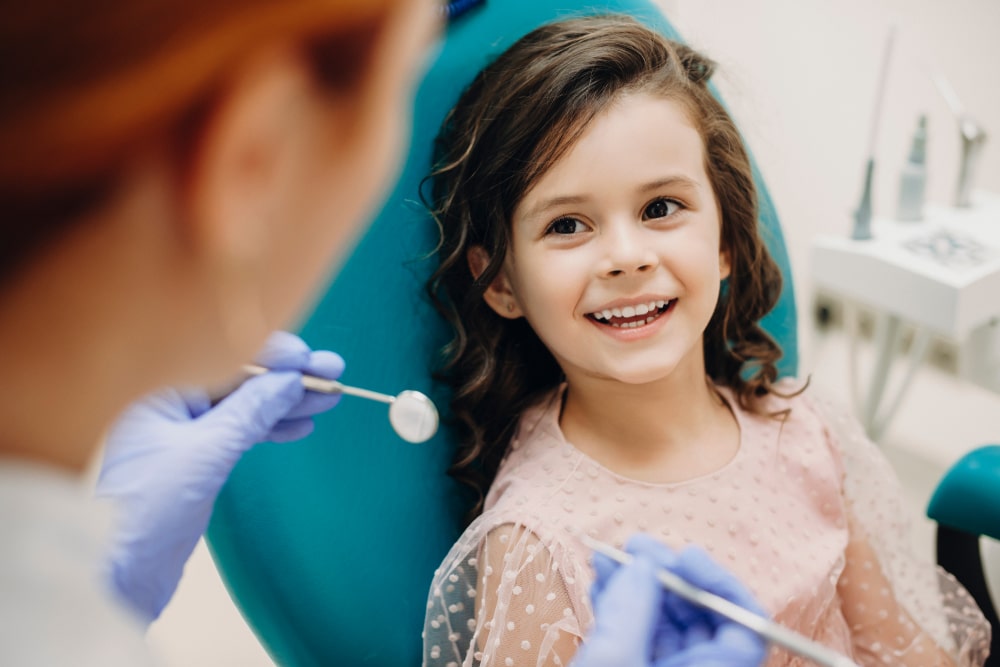 Lovely little kid smiling while talking with the pediatric dentist