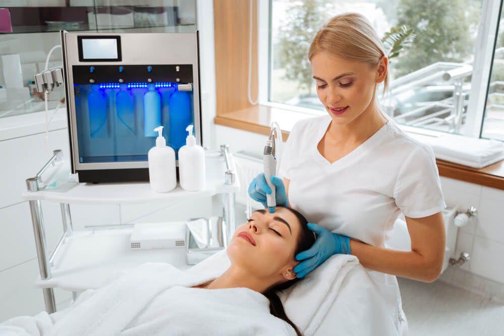 Professional skilled cosmetologist standing doing HydraFacial procedure