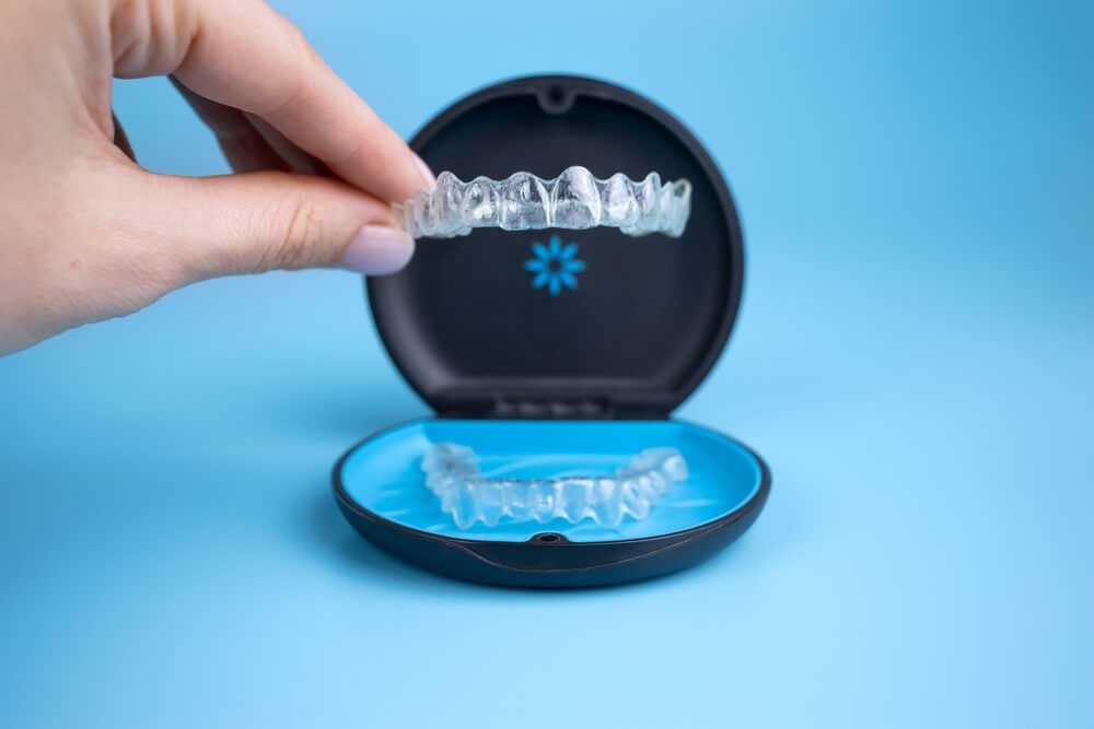 Woman holding Invisalign transparent retainers with box