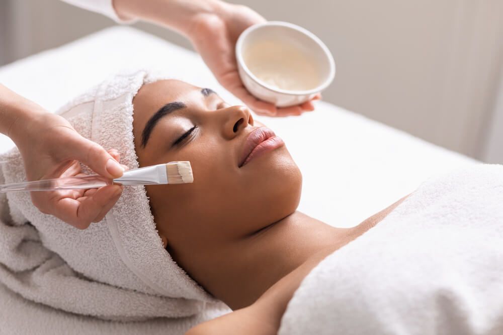 Spa therapist applying face mask on woman