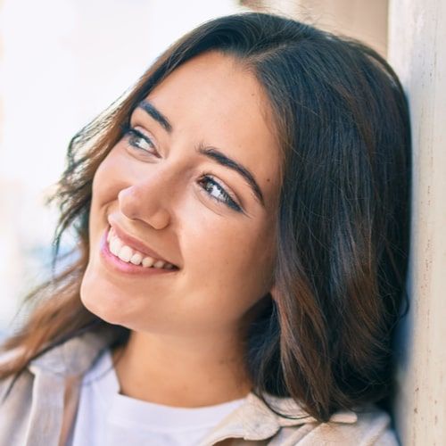 Young woman smiling happy leaning on the wall at the city.