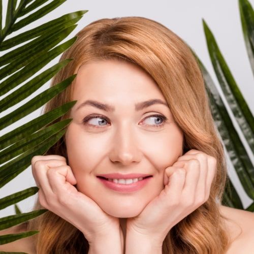 Attractive woman with leaves thinking facial product