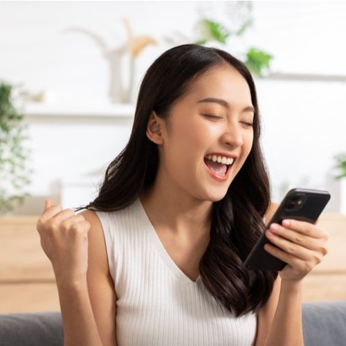 Millennial young woman looking mobile phone laughing