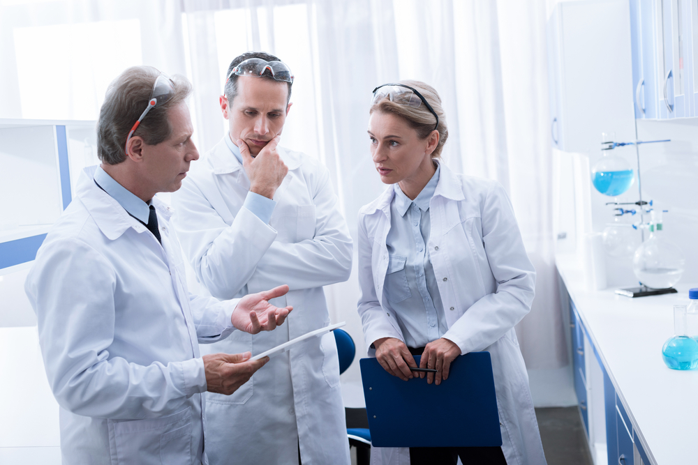 Concentrated,Colleagues,In,White,Coats,Standing,And,Talking,In,Chemical