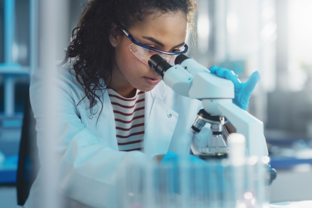 Medical Science Laboratory: Portrait of Beautiful Black Scientist Looking Under Microscope Does Analysis of Test Sample.