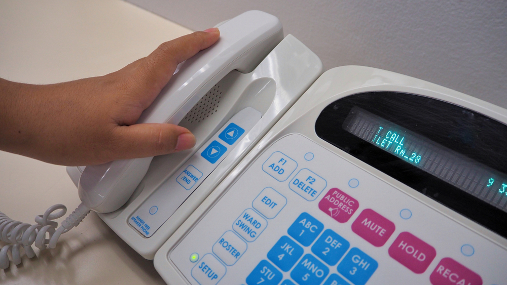 nurse's hand holding phone from electronic communication equipment.Equipment for nurse or staff when patient call for help.