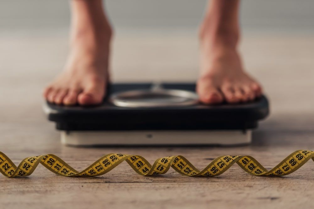 Cropped image of woman feet standing on weigh scales