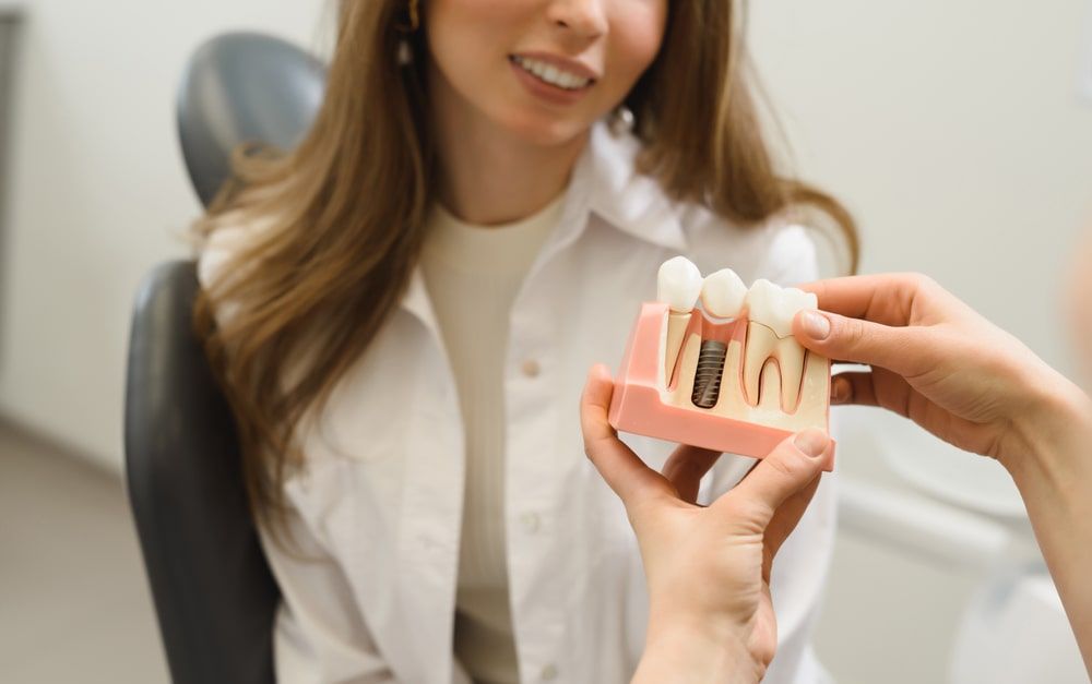 The dentist shows a model of a dental implant
