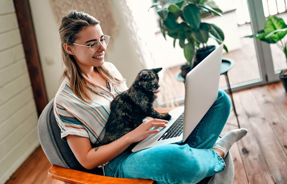 An attractive young woman in glasses is working on a laptop