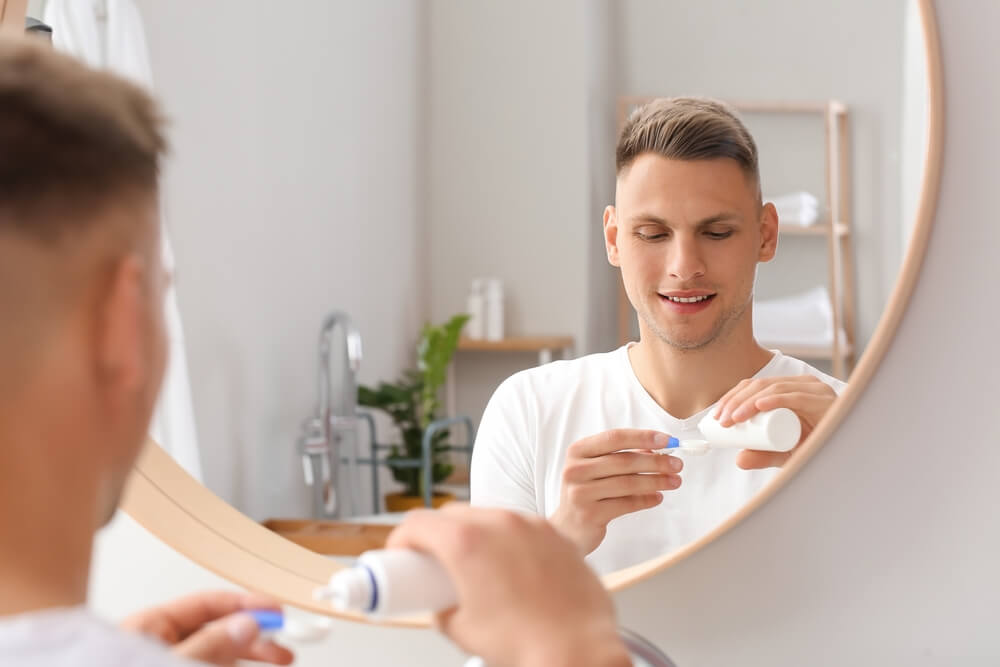 Young man with contact lenses and bottle of solution at home