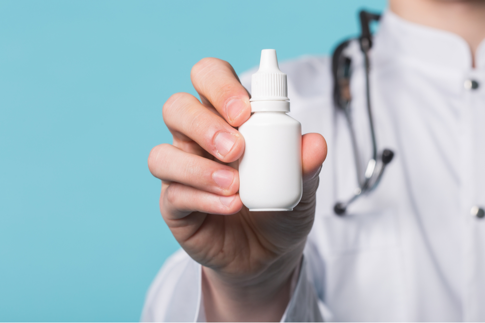 Medical drops in doctor's hand on blue background