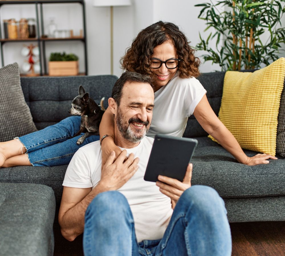 Middle age hispanic couple smiling happy and using touchpad