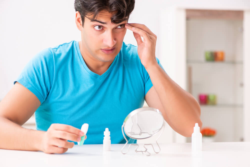 Man trying contact lenses at home