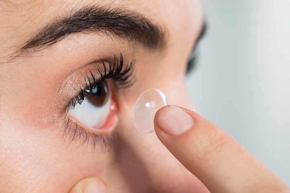 Closeup of young woman wearing contact lens at home