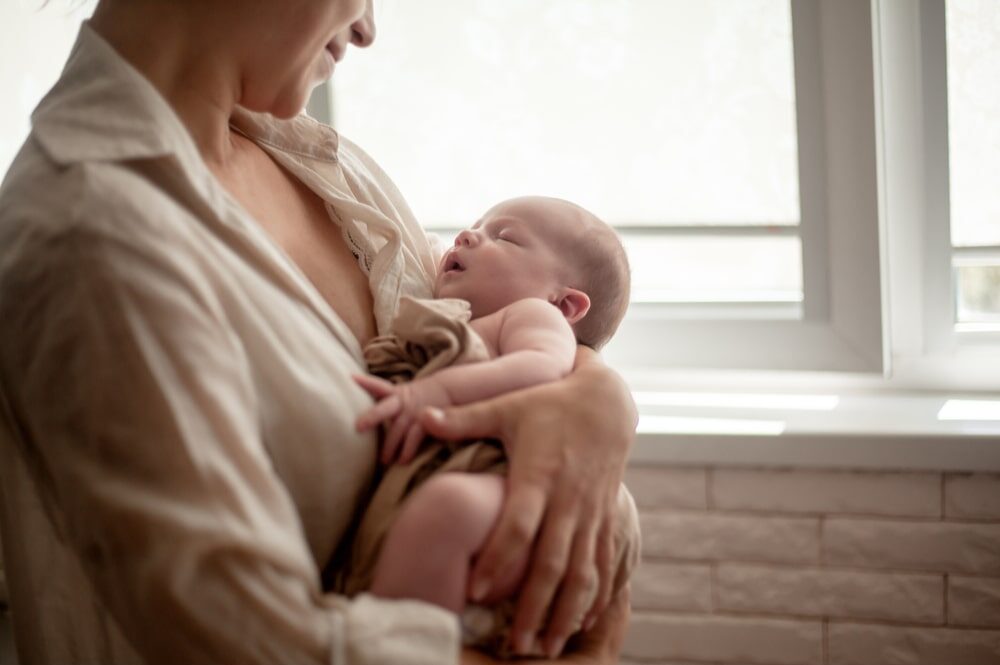 Mother holding newborn baby and breastfeedidiing little infant kid in hands