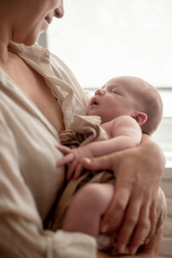 Mother holding newborn baby and breastfeedidiing little infant kid in hands
