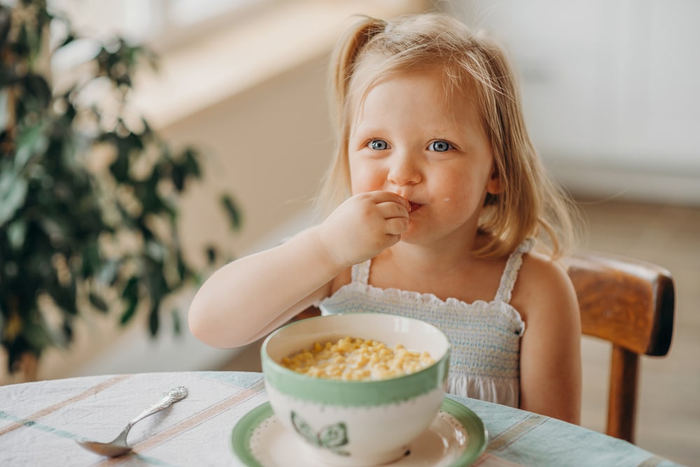 funny girl has breakfast in the morning at home in the kitchen