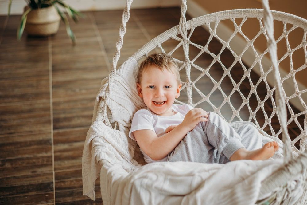 A happy child at home in a hammock smiles
