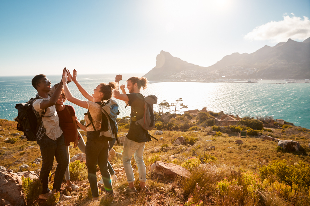 Young Adult Friends On A Hike Celebrate Reaching A Summit