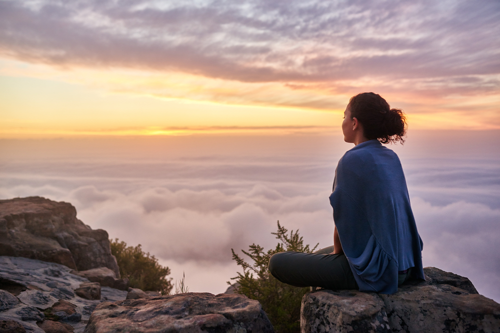 Rear View Of A Young Woman Sitting On A Mountain