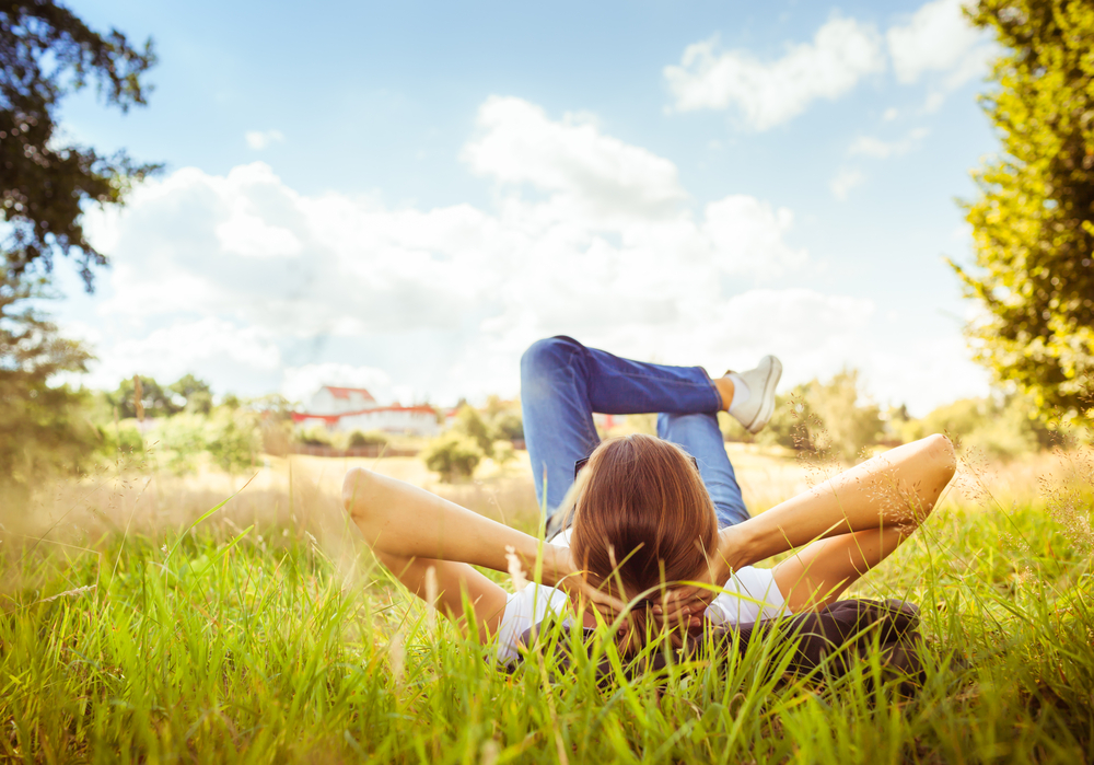 Young Woman Lying On Grass Looking Up In The Sky.