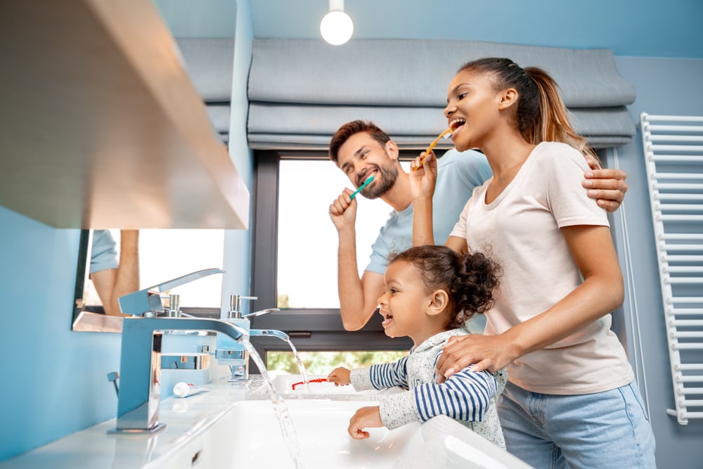 Father and mother standing together with daughter in bathroom