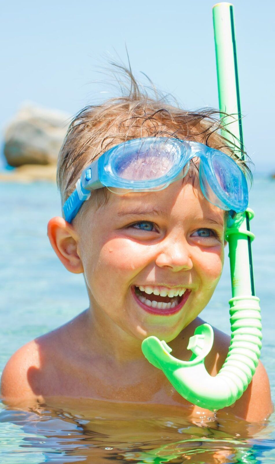 Cute boy in swimming goggles and snorkel swimming