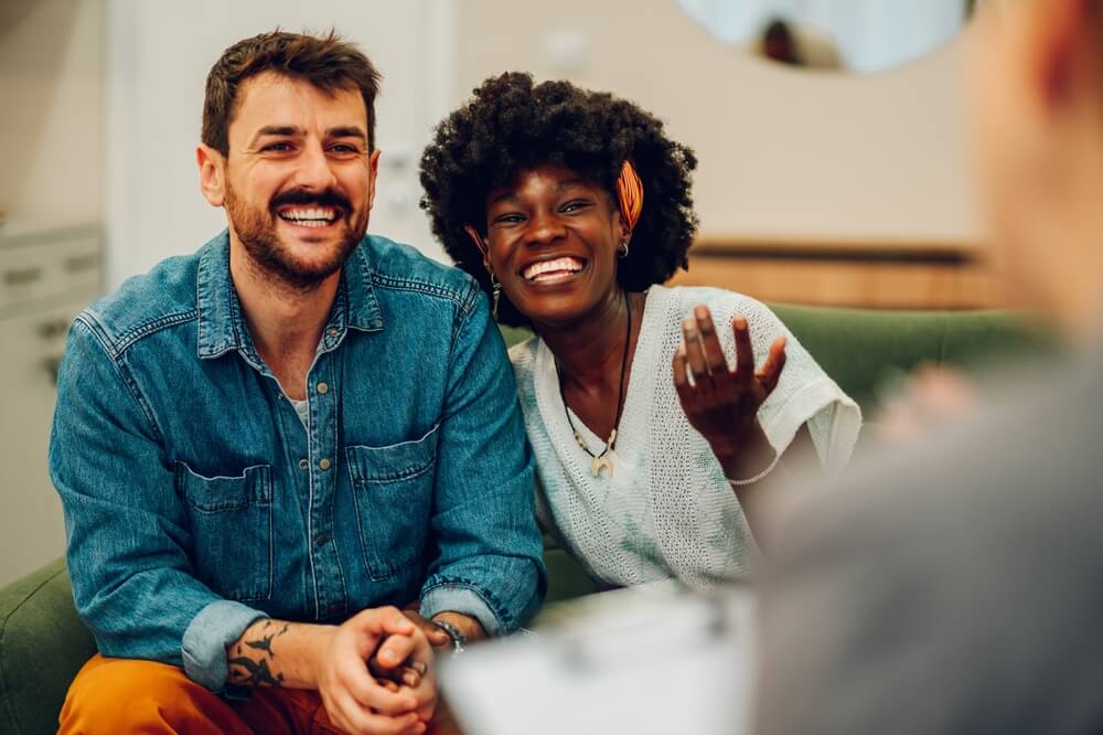 Young multiracial couple smiling because solved conflict at couple therapy session