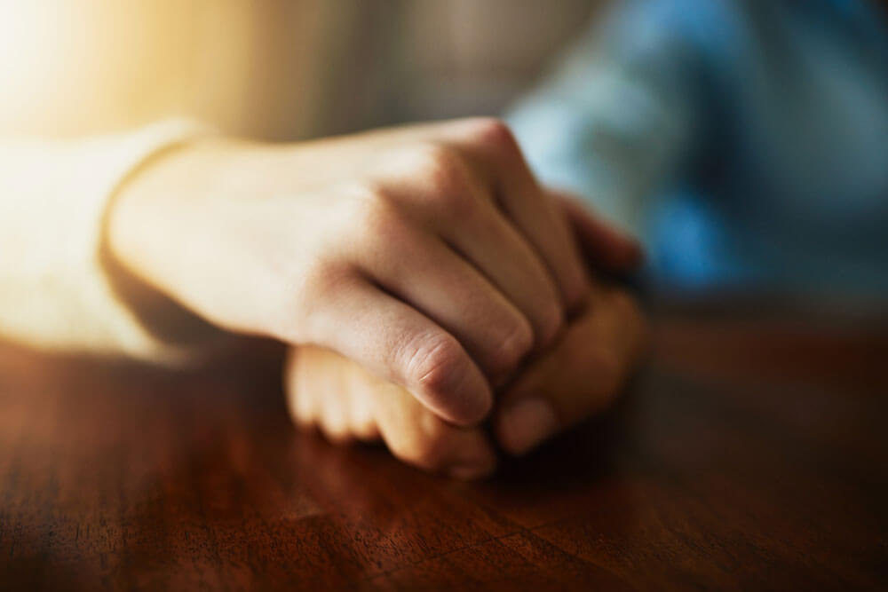 hands of people at wooden table together for hope