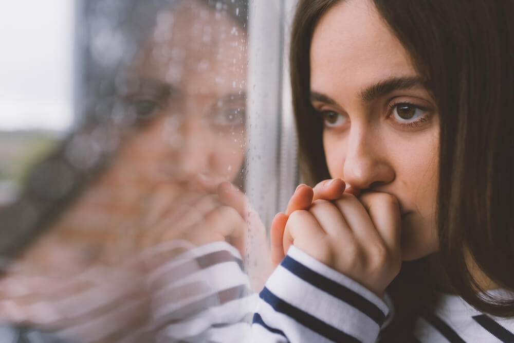 Beautiful sad woman looking at the window.