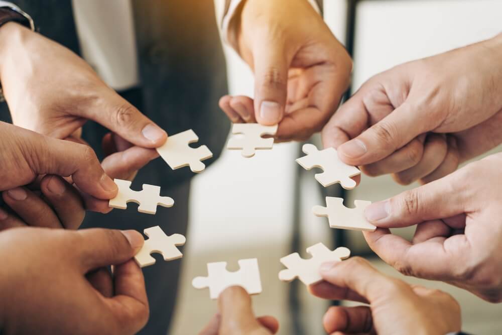 man's hands putting together puzzle pieces in the office