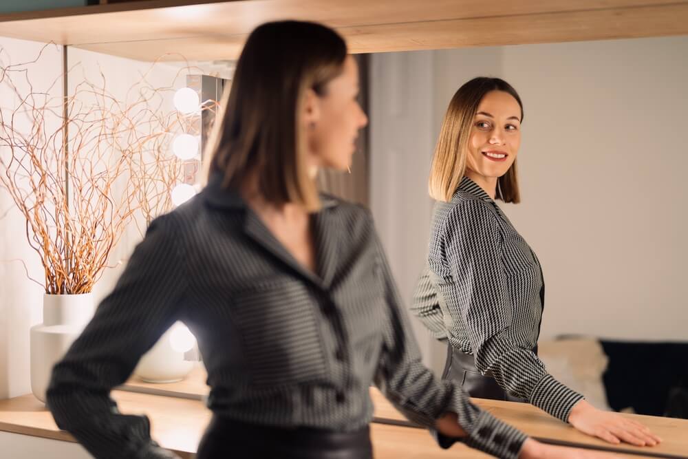 Woman looking at her reflection into the mirror