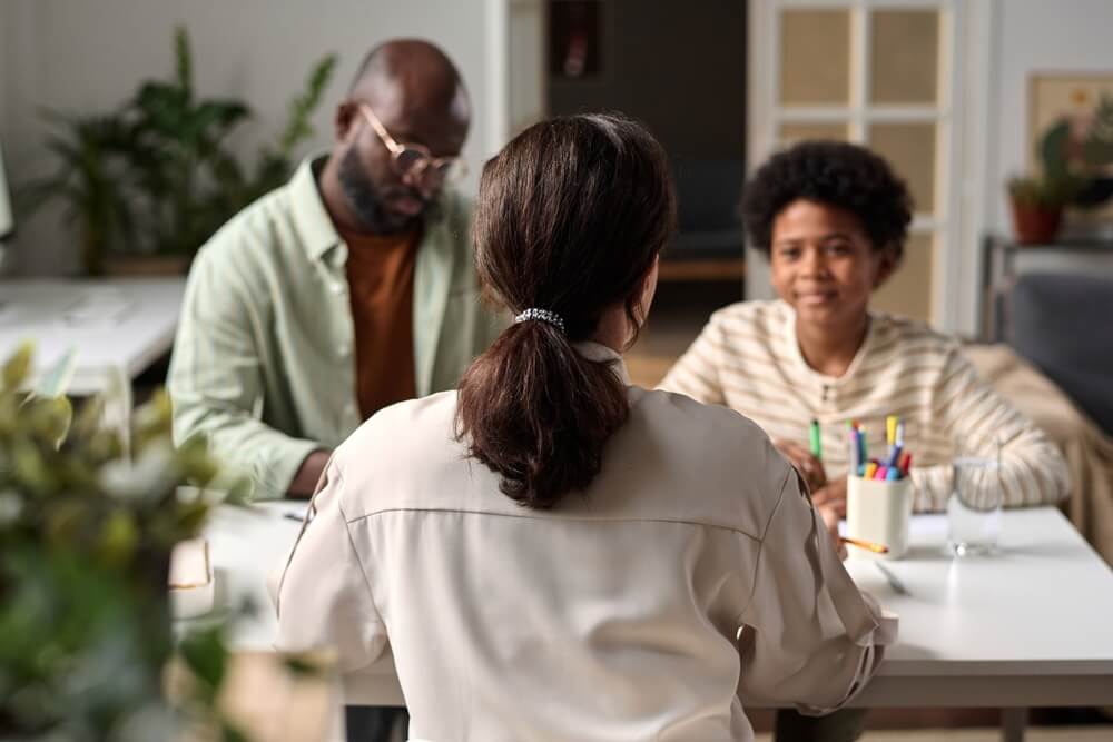 Back view of female social worker or psychologist consulting young kid