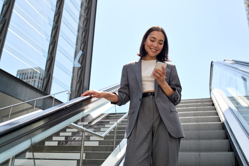 Smiling young woman wearing suit standing on urban escalator