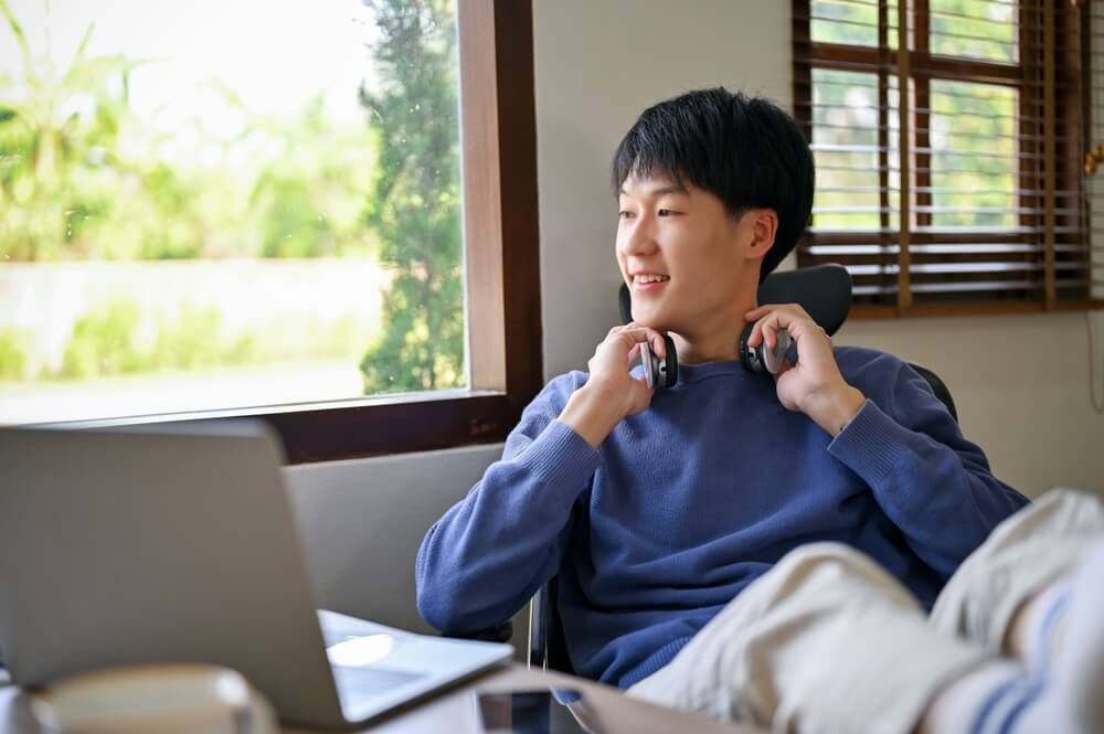 Happy and relaxed young man in comfy clothes with wireless headphones