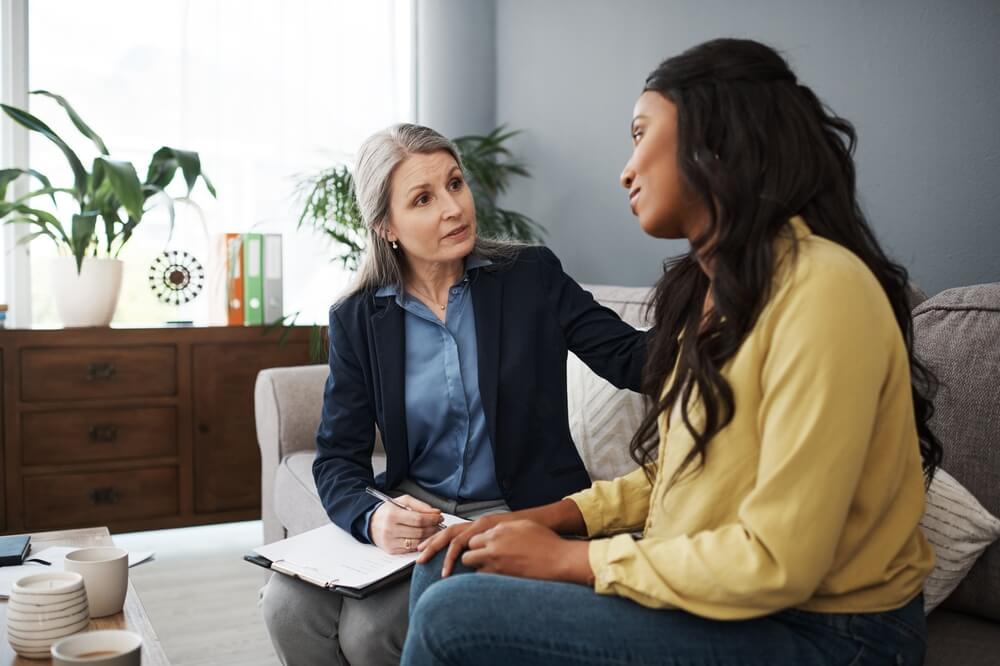 Woman, therapy and notes in office for mental health, talking with empathy