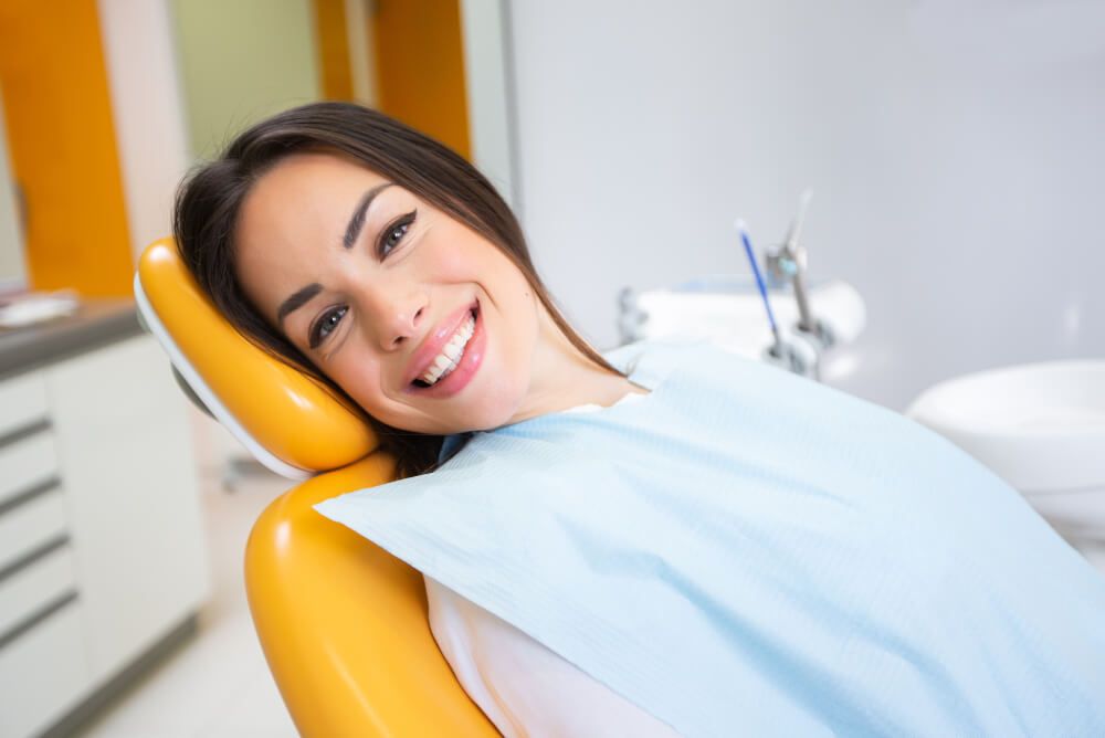 Beautiful young woman sitting on chair in dental office waiting for dental exam