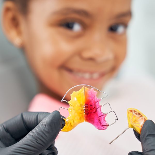 Dentist showing metal braces for smiling girl