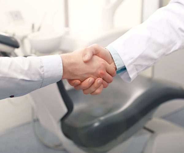 A dentist and a patient are handshaking