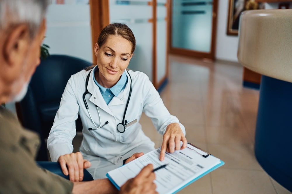 Smiling female doctor assisting senior man