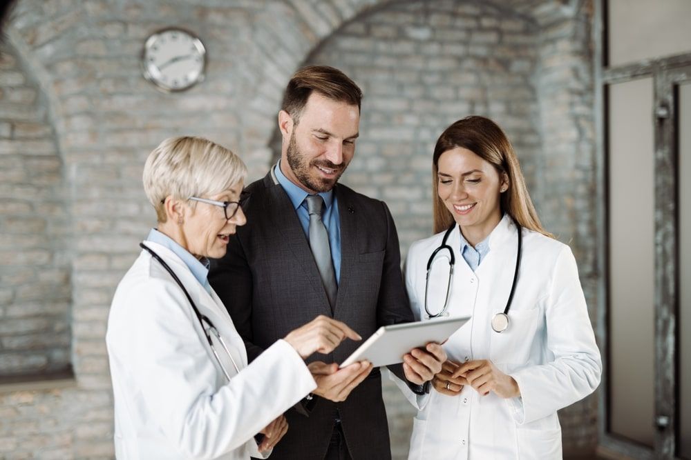 Two female doctors and man using touchpad