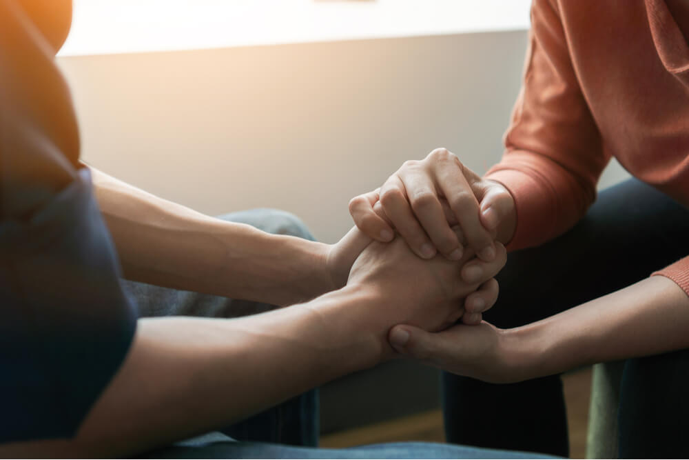 Psychologist sitting and touch hand young depressed man