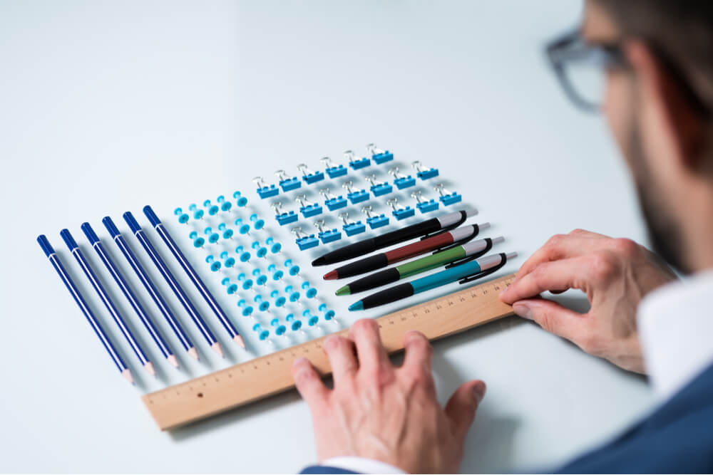 A Person's Hand Arranging Pencils And Multi Colored Pushpins