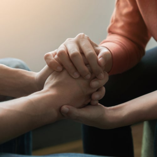 Psychologist sitting and touch hand young depressed man